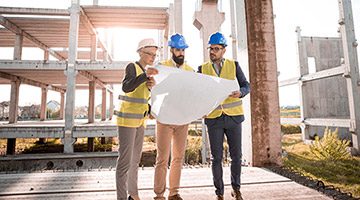 Two men and a woman looking at a blueprint