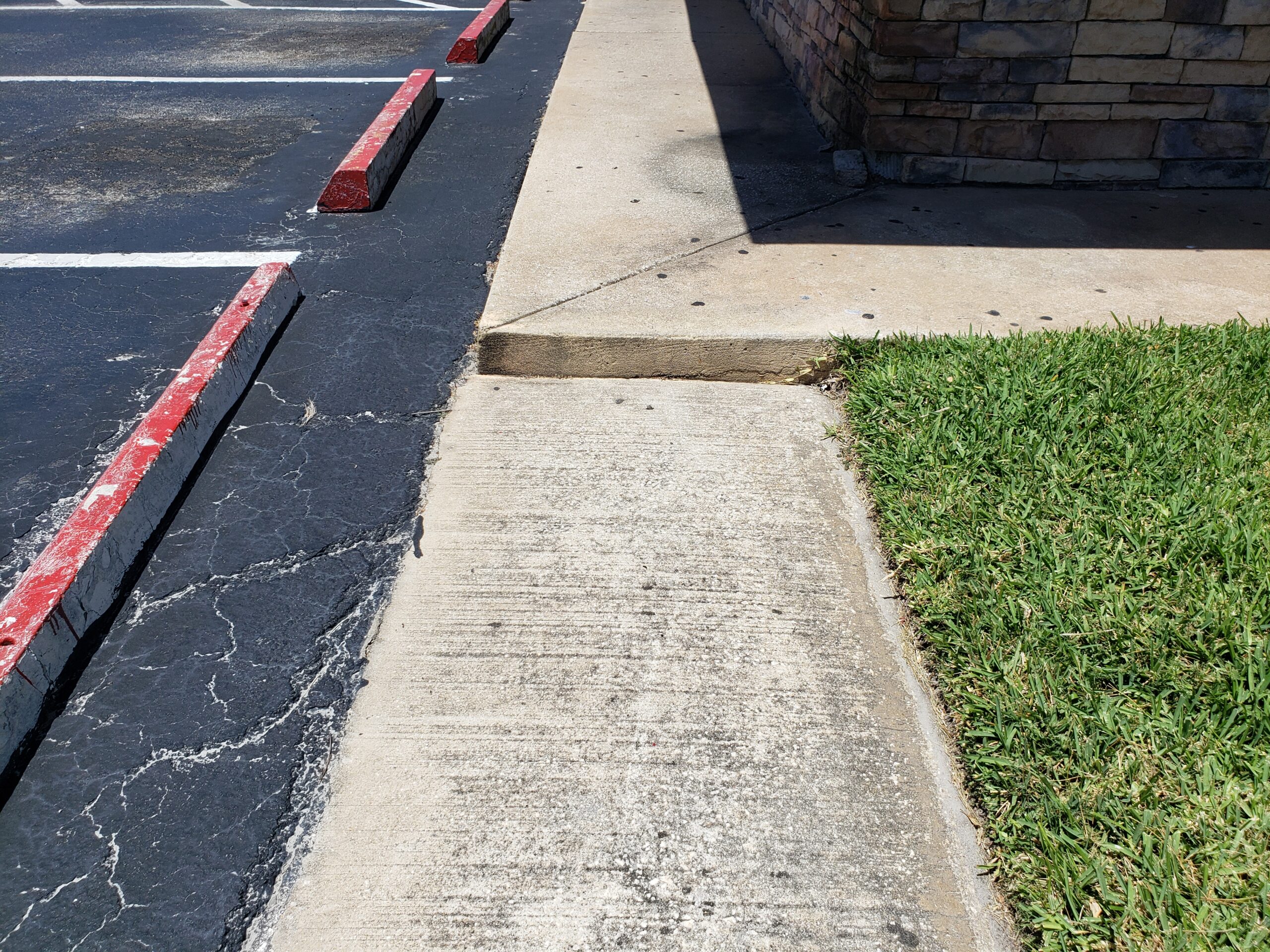 A sidewalk beside a parking lot