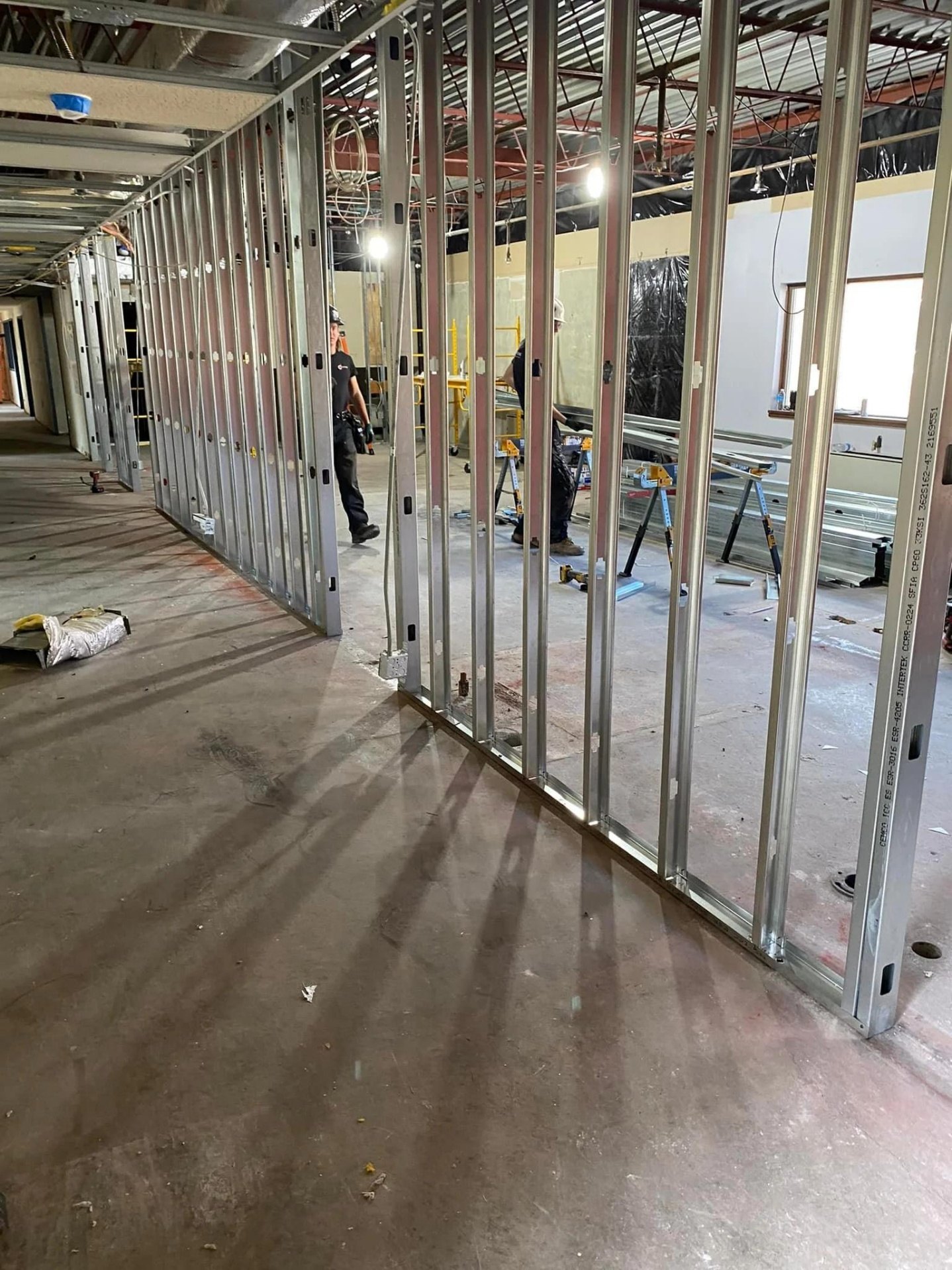 Interior construction workers behind steel partition rails