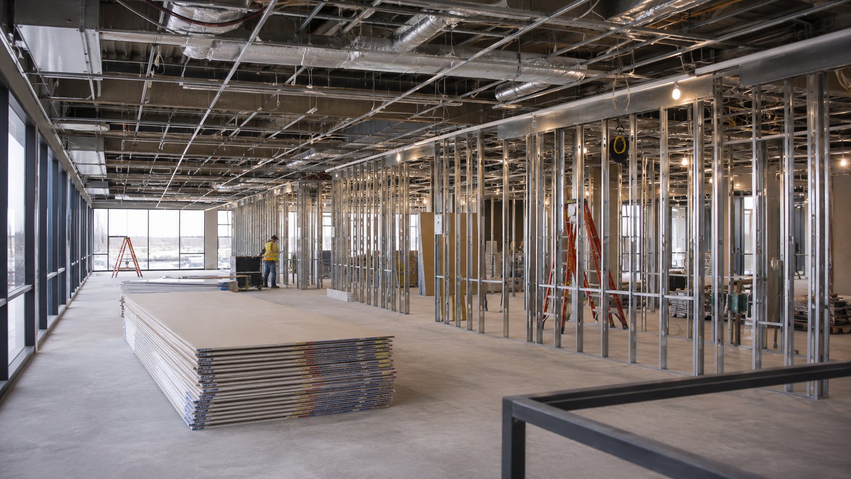 Worker by ladder in unfinished high-rise office